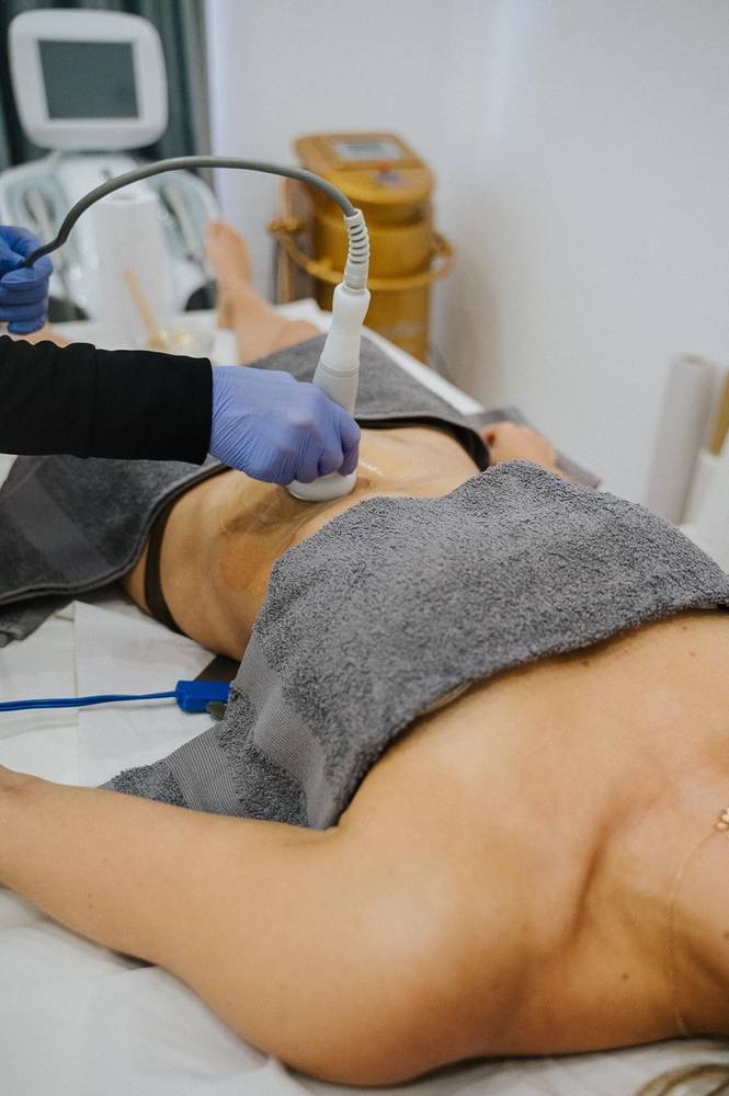Tratamento corporal com aparelho na sala do centro de estética